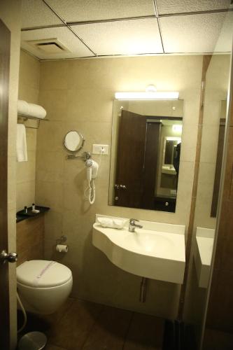 a bathroom with a sink and a toilet and a mirror at WEST FORT HOTEL in Bengaluru