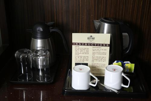 a counter with a coffee pot and cups and a box at WEST FORT HOTEL in Bangalore