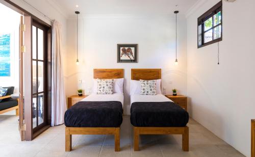 a bedroom with two beds and two windows at Villa Toru - Stylish luxury in Legian, tranquil location, walk to beach in Legian