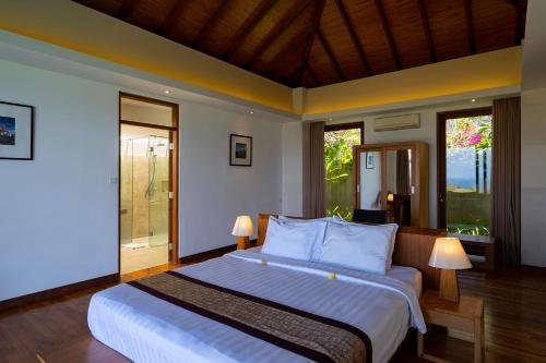 a bedroom with a large bed in a room with windows at Moritz Palm Villa in Uluwatu
