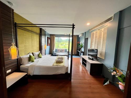 a bedroom with a canopy bed and a television at โรงแรมวิลลา พาราดี in Ban Khanong Phra Tai