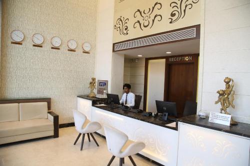 a man sitting at a reception desk with a laptop at WEST FORT HOTEL in Bengaluru