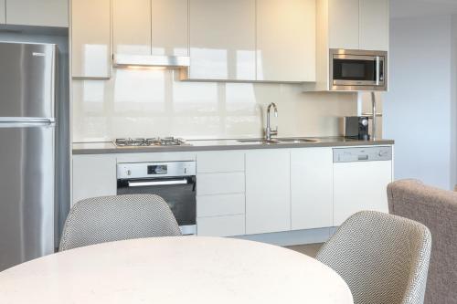 a kitchen with white cabinets and a table with chairs at Meriton Suites Adelaide Street, Brisbane in Brisbane