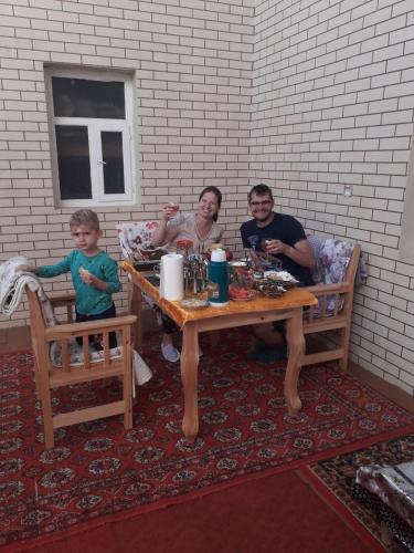 Un grupo de personas sentadas en una mesa con un niño. en Hotel Allanazar Ota, en Khiva