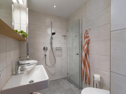 La salle de bains blanche est pourvue d'une douche et d'un lavabo. dans l'établissement Haus Dorfblick, à Ellmau