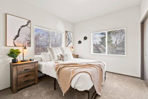 a bedroom with a bed and a table and two windows at Spacious NEW 2 bed 2 bath apt by Downtown Spokane in Spokane