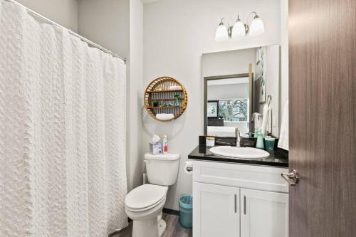 La salle de bains est pourvue de toilettes, d'un lavabo et d'un miroir. dans l'établissement Spacious NEW 2 bed 2 bath apt by Downtown Spokane, à Spokane