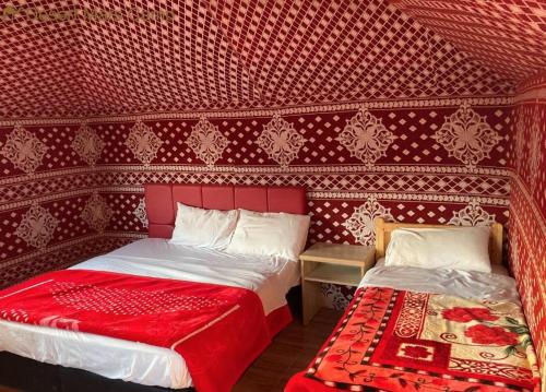 a bedroom with two beds and a red wall at Wadi Rum Nights in Wadi Rum