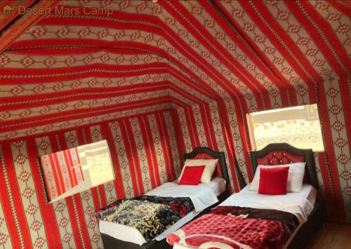 two beds in a room with a red wall at Wadi Rum Nights in Wadi Rum
