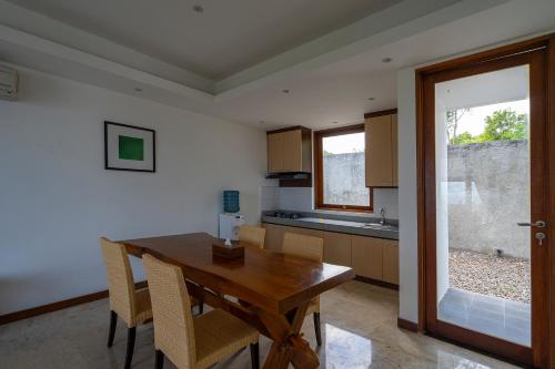a kitchen with a wooden table and chairs at Moritz Palm Villa in Uluwatu