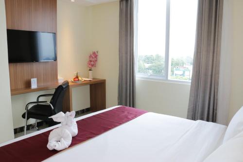 a hotel room with a white stuffed animal sitting on a bed at Horison Sentani in Ifaar