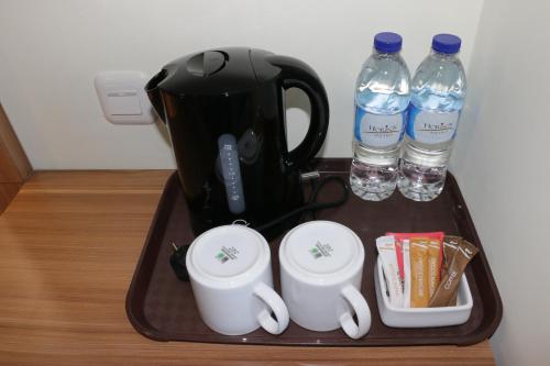 a tray with a coffee maker and two bottles of water at Horison Sentani in Ifaar