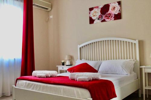 a bedroom with a white bed with red and white pillows at Casa Al Porto in Palermo