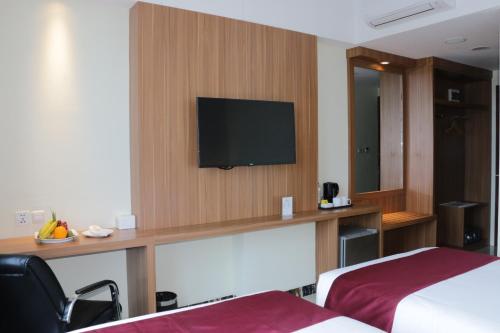 a hotel room with a flat screen tv on a wall at Horison Sentani in Ifaar