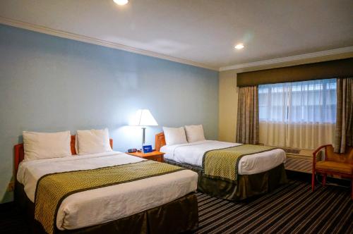 パロアルトにあるホテル パーマニのベッド2台と窓が備わるホテルルームです。