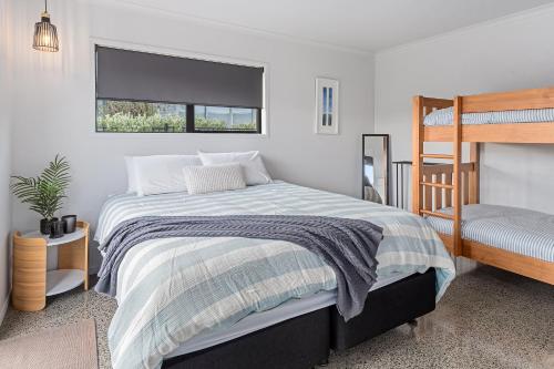 um quarto com uma cama e um beliche em A Couple's Retreat - Mangawhai Heads Holiday Home em Mangawhai
