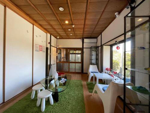 a room with a glass table and white chairs at Bamboo Village Guest House in Naoshima