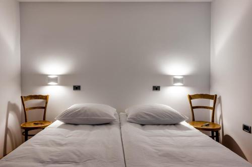 a bedroom with a bed with two pillows and two chairs at Karst house Žan Pliskovica with private pool in Dutovlje