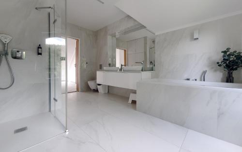 a white bathroom with a tub and a sink at Holimo Hotel in Stronie Śląskie