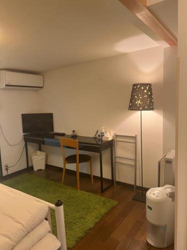a bedroom with a desk and a bed and a table at Bamboo Village Guest House in Naoshima