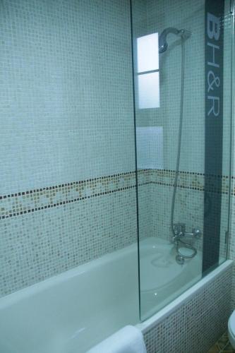 a bathroom with a tub and a shower with a glass door at Hotel Pizarro in Humanes de Madrid