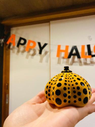 a person holding a polka dot ball in front of a happy hall at Bamboo Village Guest House in Naoshima