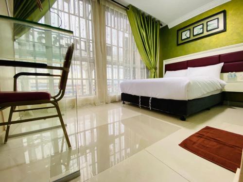 a bedroom with a bed and a chair in it at Surya Boutique Hotel Klang in Klang