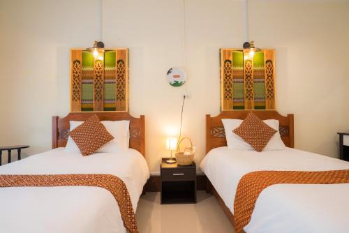 um quarto com 2 camas e lençóis brancos em Gita's House em Chiang Rai