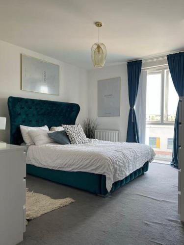 a bedroom with a large bed with a blue headboard at Lovely One Bedroom Apartment, with on-site Parking in Thamesmead