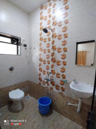 bagno con servizi igienici e lavandino con foglie sul muro di Swami Nivas a Malwan