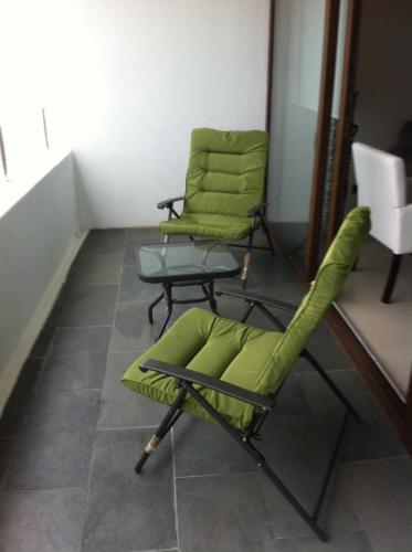 two green chairs and a table in a room at Jardin del Mar Costanera in Coquimbo
