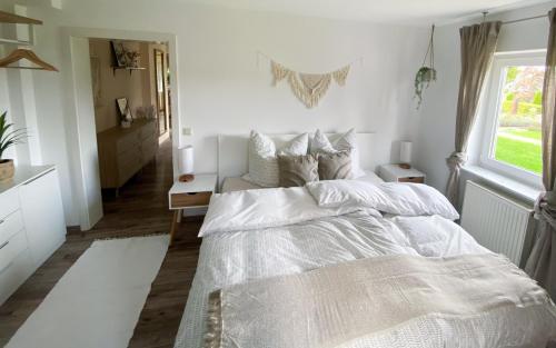 a white bedroom with a bed and a window at Schöne Wohnung mit Terrasse & Blick ins Grüne in Dormettingen