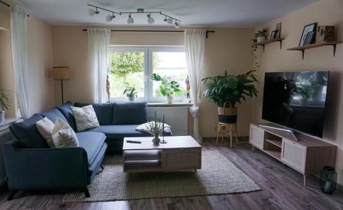 a living room with a blue couch and a tv at Schöne Wohnung mit Terrasse & Blick ins Grüne in Dormettingen