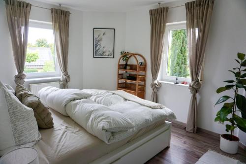 a bedroom with a bed with white sheets and a window at Schöne Wohnung mit Terrasse & Blick ins Grüne in Dormettingen