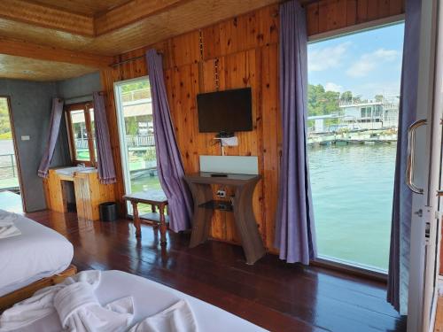 a bedroom with a bed and a tv and a window at บ้านไร่ วรรณ วาลย์ รีสอร์ท in Tha Kradan
