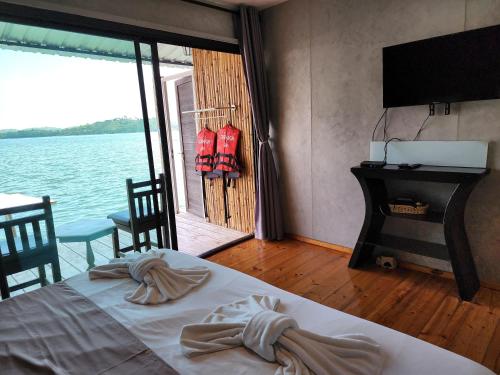 a bedroom with a bed and a view of the water at บ้านไร่ วรรณ วาลย์ รีสอร์ท in Tha Kradan