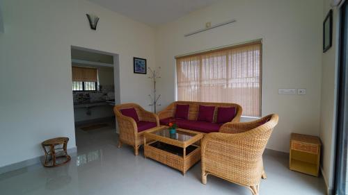 a living room with a couch and wicker chairs at Vrindhavan Mist City Resorts in Kanthalloor
