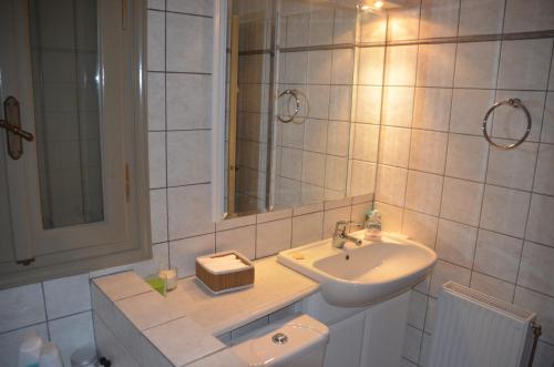 biała łazienka z umywalką i lustrem w obiekcie The Stonehouse w mieście Stemnitsa