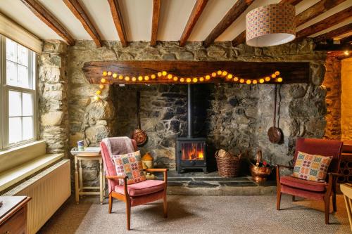 ドルゲラウにあるFinest Retreats - Hope House - Ty Gobaithの石造りの暖炉と椅子2脚付きのリビングルーム