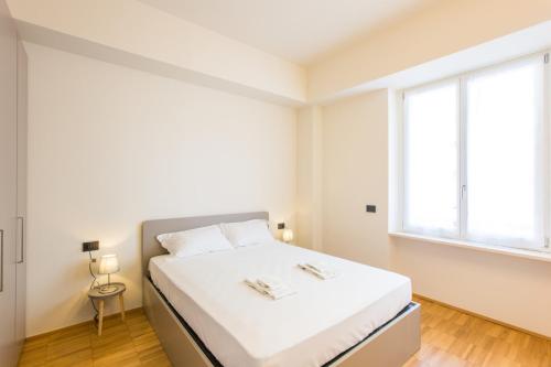 Habitación blanca con cama y ventana en Easylife - Moderno bilocale in zona Porta Romana en Milán