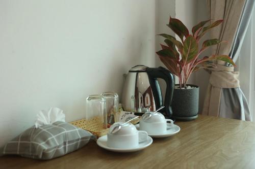 uma mesa com duas chávenas e uma cafeteira e uma planta em New Forest Patong em Praia de Patong