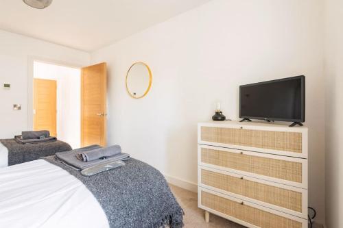 a bedroom with a bed and a tv on a dresser at Cliff Top Heights-Beach front house near Brighton in Rottingdean