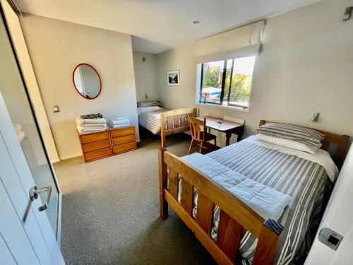 聖阿諾的住宿－The bach，一间卧室配有两张床、一张桌子和一面镜子