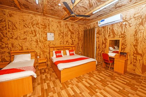 a bedroom with two beds and a table and a desk at OYO 138 Gulf Sand Motel in Barka