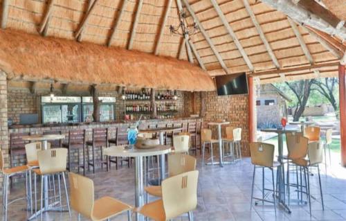 un restaurante con mesas y sillas y un bar en Kwadiwa Ranch, en Baines Drift