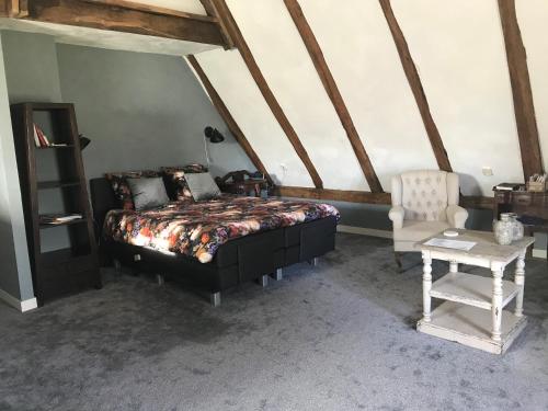 een slaapkamer met een bed, een tafel en een stoel bij Een mooie plek in Markelo