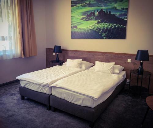 een bed in een slaapkamer met een schilderij aan de muur bij Garda Hotel in Szombathely