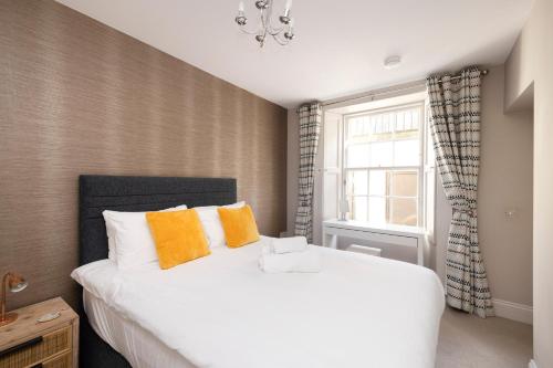 een slaapkamer met een groot wit bed met oranje kussens bij JOIVY Splendid 1-BR Flat near Edinburgh Castle in Edinburgh
