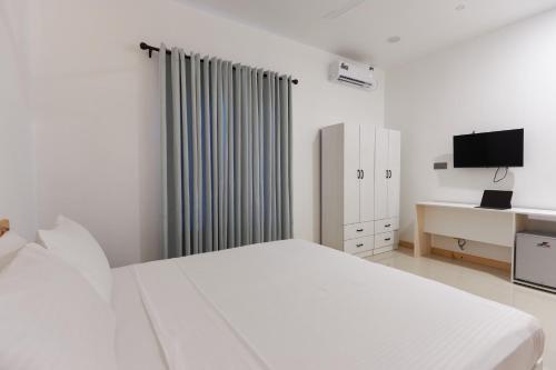 a white bedroom with a bed and a tv at Splendour Grand in Maalhos