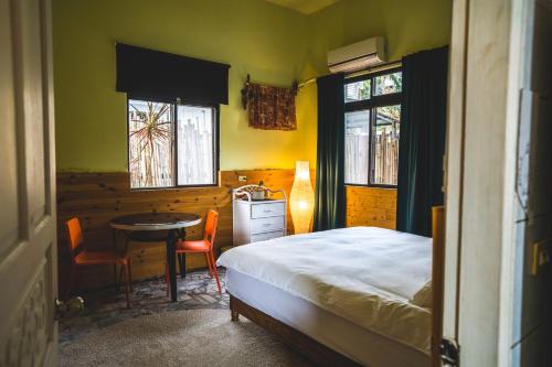 a bedroom with a bed and a table and two windows at Wild East Country House in Manzhou